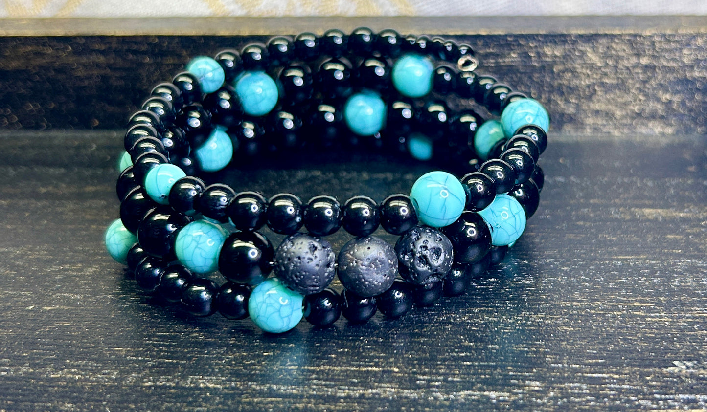 Black and turquoise blue beaded aromatherapy bracelet on a wooden surface