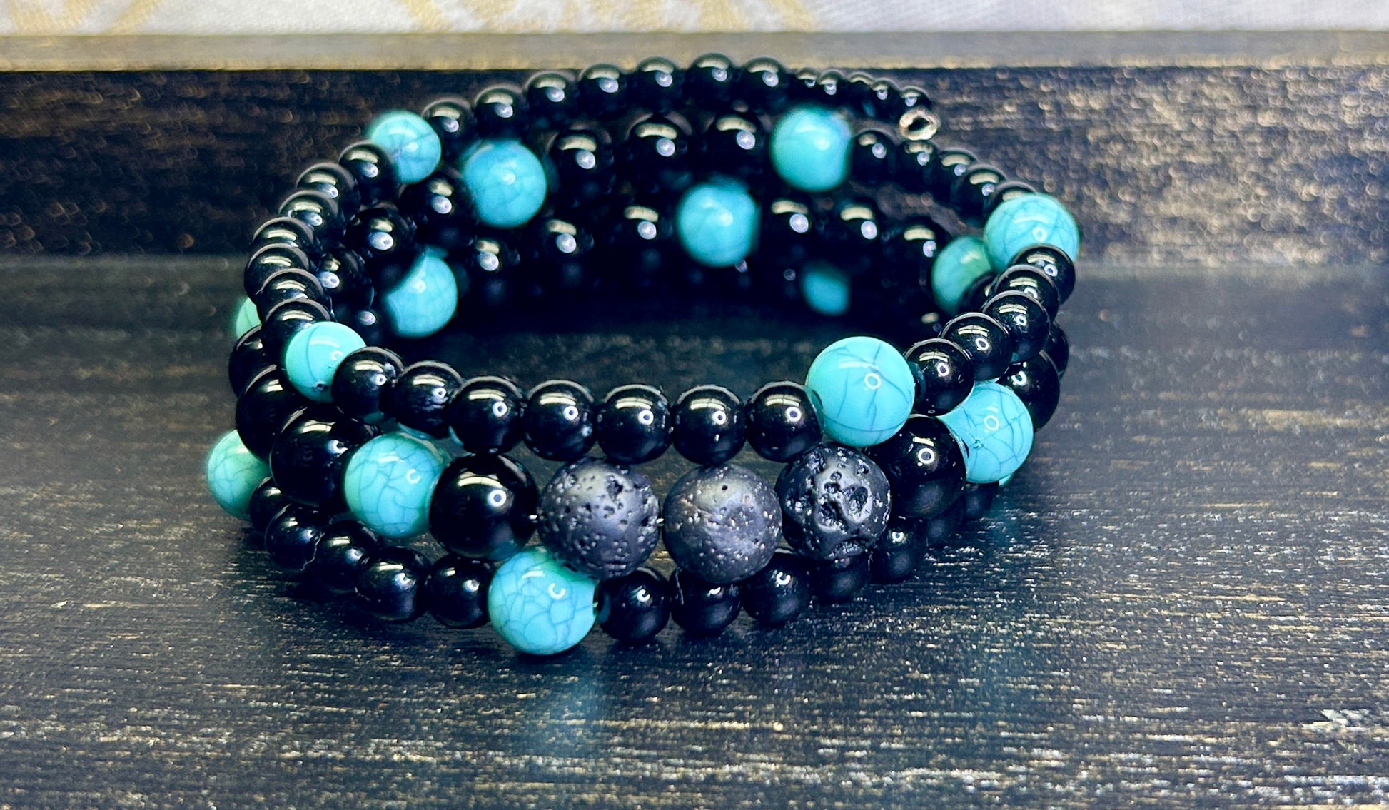 Black and turquoise blue beaded aromatherapy bracelet on a wooden surface